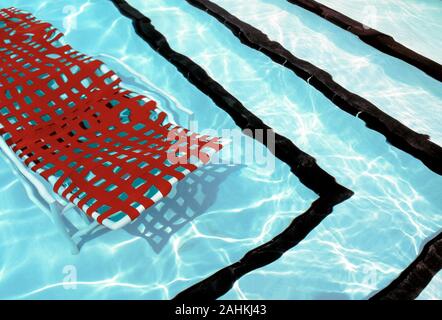 High angle view of a deck chair submersed in a swimming pool. Stock Photo