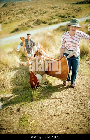 Family carrying canoe uphill Stock Photo
