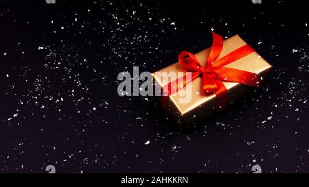 Golden gift with a red ribbon on a black background. Rozhdenvensky and New Year's concept. discounts and black friday Stock Photo
