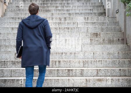 Young man Holding Computer Laptop Walking Up Stairs outdoor . Stock Photo