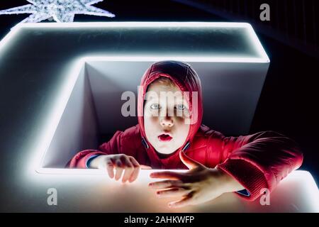 Funny night portrait of boy with grimaces lit by neon. Stock Photo