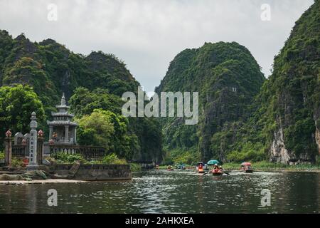 Tourists in boats row up the Ngo Dong River through limestone mountains and caves in Tam Coc, Ninh Binh Province, Vietnam Stock Photo