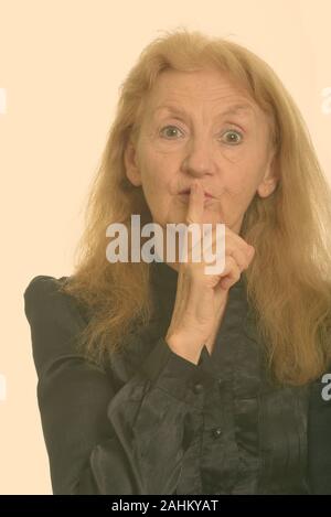 Close up of senior businesswoman with finger on lips Stock Photo