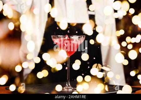 Barman in making cocktail at a nightclub. Nightlife concept. No face. Pouring into glass.. Horizontal with festive bokeh lights Stock Photo