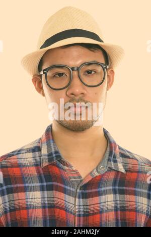 Face of young Asian man wearing eyeglasses and hat Stock Photo