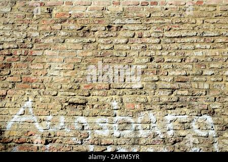 Background from an old historical wall made of burnt bricks, on which the word "Augsburg" was smeared with white paint Stock Photo