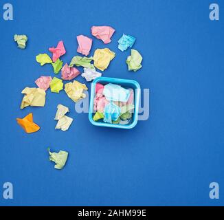 stationery blue metal bucket filled with crumpled multi-colored stickers, top view, blue background Stock Photo