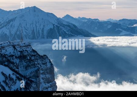 layer of clouds with tyndall effect at the flank of Mount Niesen at the entrance of Simmental Valley Stock Photo