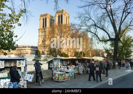 Rows of stalls on Quai de Montebello selling artwork, gifts and souvenirs as people walk past and Cathédrale Notre-Dame de Paris in background, Paris, Stock Photo