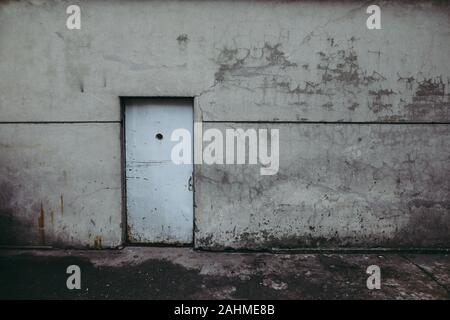 Grungy worn out metallic door in the wall of an old prison of the communist Romanian Securitate. Stock Photo