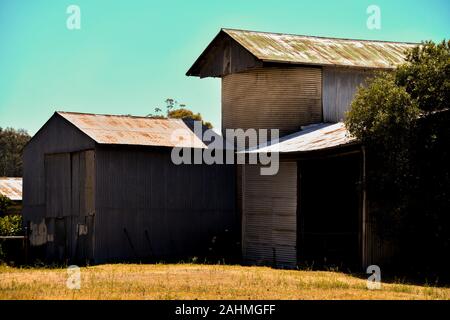 Old Rusted Corrugated Iron Barn Sheds with Silo on Farm Stock Photo