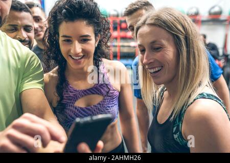 Athletes looking at the mobile of a gym mate Stock Photo