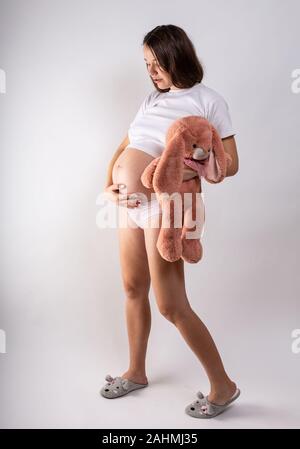 Close-up pregnant woman's belly with Hare toy. Beautiful pregnant woman. Pregnancy, parenthood, preparation and expectation concept. Stock Photo