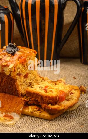 A sliced home-made Christmas cake on a wooden Board and ceramic tableware on a table covered with a homespun cloth Stock Photo