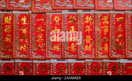 Chinese new year greetings printed with gold color on red paper hanging at a store, the chinese words mean wealth, prosperity and wishes come true Stock Photo