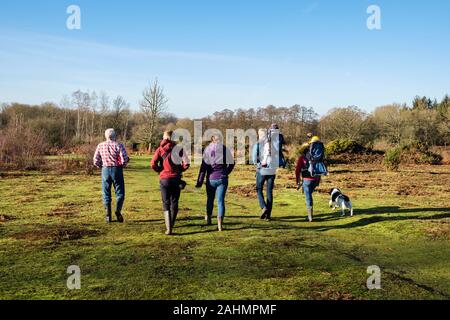 Three generations of a family walking with a dog on heathland in Kent Wildlife Trust nature reserve in winter. Hothfield Heathlands Ashford England UK Stock Photo