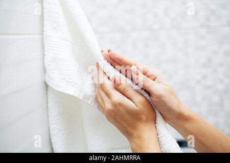 Close up hands use white towel in light bathroom Stock Photo