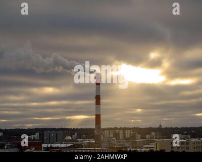 Smoking factory big tall pipe. Red and white pipe, cloudy sunset sky on background. Rainy day. Sky panorama for backdrop wallpaper, desktop. Copy space. Concept of ecology problems. Filtered image. Stock Photo