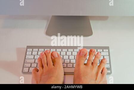 Man's feet typing keyboard. Stock Photo