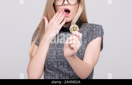 Young frightened businesswoman holding bitcoin concept Stock Photo