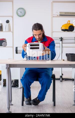 The young male contractor repairing toaster at workshop Stock Photo
