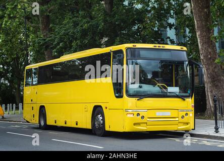 A bright yellow coach waiting to collect passengers for a trip. Stock Photo