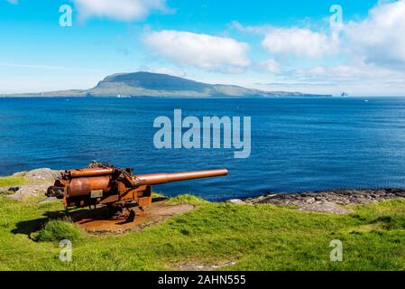 British gun from the warship  in Skansin fortress of Torshavn,  Faroese island of Streymoy. Atlantic Ocean and Nolsoy island are at background Stock Photo