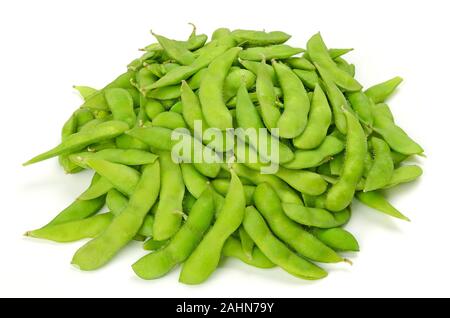 Pile of edamame on white surface. Green soybeans in the pod. Unripe soya beans, Maodou. Glycine max. Legume, edible after cooking. Rich protein source Stock Photo