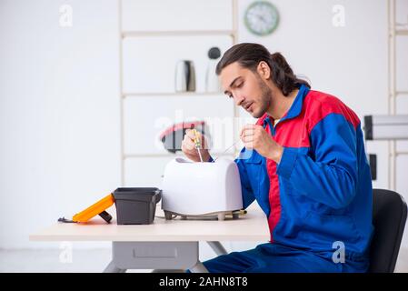 The young male contractor repairing toaster at workshop Stock Photo