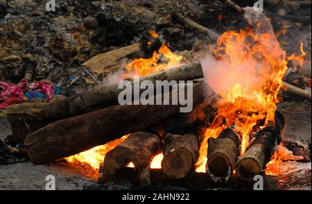 The body of a Hindu person is being cremated in the traditional way and,surrounded by similar pyres the intense heat,smoke and odors are overwhelming. Stock Photo