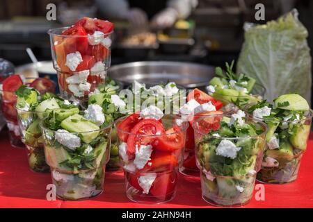 healthy street food vegetables salad with cucumber, tomato, soft cheese and parsley in plastic cups. portions closeup Stock Photo