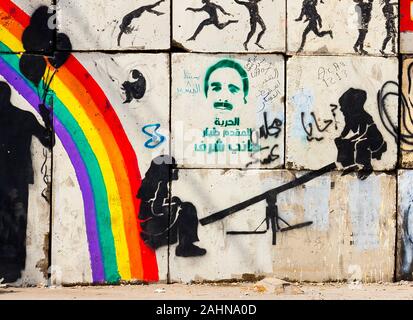 Egypt, Cairo, graffiti of the Egyptian revolution on a wall blocking a street  adjacent  to sharia Mohamed Mahmoud. Children play swing near a rainbow. Stock Photo