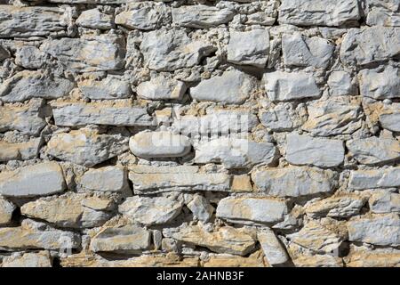 A beautiful White Stone Wall Background with a layer of yellow dirt on it. Stock Photo