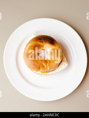 top down shot of egg bacon bagel breakfast sandwich on a white plate Stock Photo