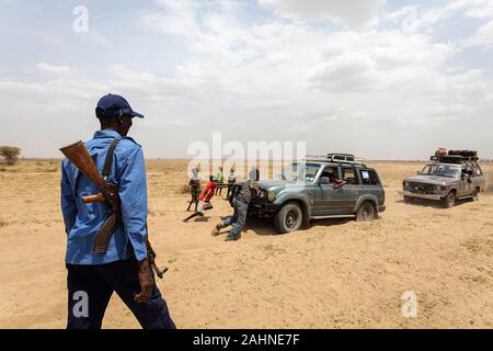 Armed men push their car stuck in soft sand near Lake turkana, border of Ethiopia and Kenya Stock Photo