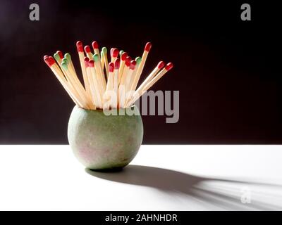 Long household wooden matches in pot backlit on black, white background. Stock Photo