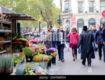 Busy street in Holborn, Central London, with corner flower stand, and people walking by. Stock Photo