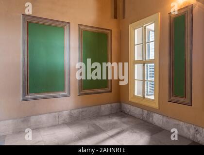 Three beautiful elegant rectangular green frames with ornate border and wooden window with green shutters on orange wall with white marble floor, in abandoned old building Stock Photo