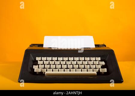 Black Typewriter isolated in yellow background Stock Photo