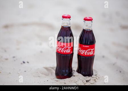 Sochi, RUSSIA - November 23, 2019: two glass bottles of Coca-Cola on white sand beach. Stock Photo