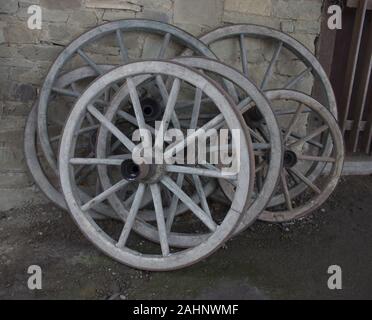 Old wooden wheels on a carriage leaning against a wall Stock Photo