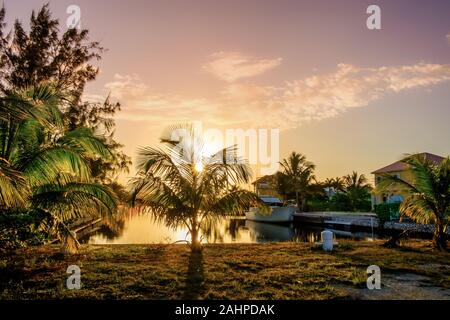 Grand Cayman, Cayman Island, Jan 2019, boat moored in a residential area at sunset on a canal leading to the Caribbean Sea in West Bay Stock Photo