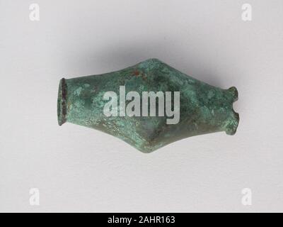 Ancient Greek. Biconical Bead. 800 BC–600 BC. Greece. Bronze These precious bronzes objects are votives, or devotional gifts, made for gods. They come in many forms. Some are miniature sculptures of animals, mostly depicting horses, deer, and birds. Others are items of personal adornment, including beads and brooches. Quite a few seem once to have been attached to something else. This assemblage is characteristic of the thousands of votives that were hung from sacred trees or placed in sanctuaries around Greece. Once a shrine was full, the votives were gathered together and ceremonially buried Stock Photo