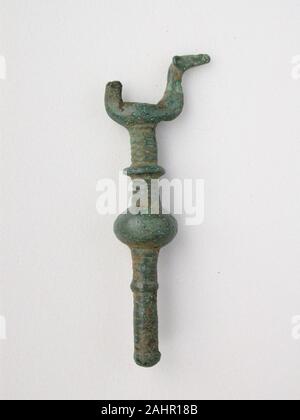 Ancient Greek. Double Birds on Knobbed Stand. 800 BC–600 BC. Thessaly. Bronze This precious bronze object is a votive, or devotional gift, made as an offering to the gods. They come in many forms, such as animals, beads and brooches. Many seem once to have been attached to something else. Votives were hung from sacred trees or placed in sanctuaries around Greece. Once a shrine was full, the votives were ceremonially buried to make room for more offerings. Stock Photo