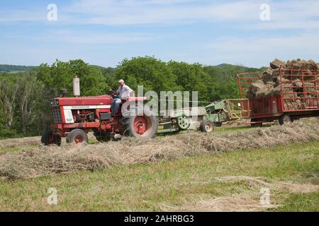 Man on International Harvester Farmall tractor, baling hay in a field in Galena, Illinois, USA.  (For editorial use only) Stock Photo