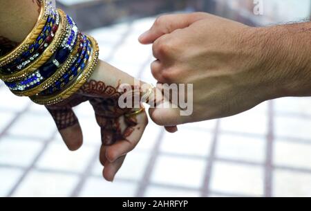 Closeup image of a man's and woman's hands holding little fingers of each other isolated over white wall background. Stock Photo