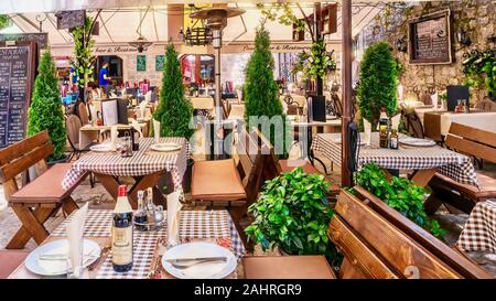 Kotor, Montenegro - June 5, 2016. An outdoor restaurant catering to foreign tourists has its tables set and a menu board prepared for lunch. Stock Photo