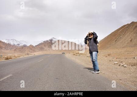 Travelers thai woman travel visit and posing for take photo with landscape high range mountain on Srinagar Leh Ladakh highway at Leh Ladakh village in Stock Photo