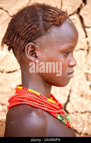 Portrait of a girl from Dassanech tribe in front of a cracked walls of a traditional house, Omo valley, Ethiopia Stock Photo