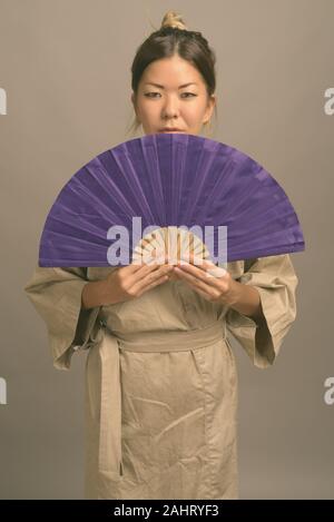Studio shot of young beautiful Kazakh woman wearing traditional clothes against gray background Stock Photo